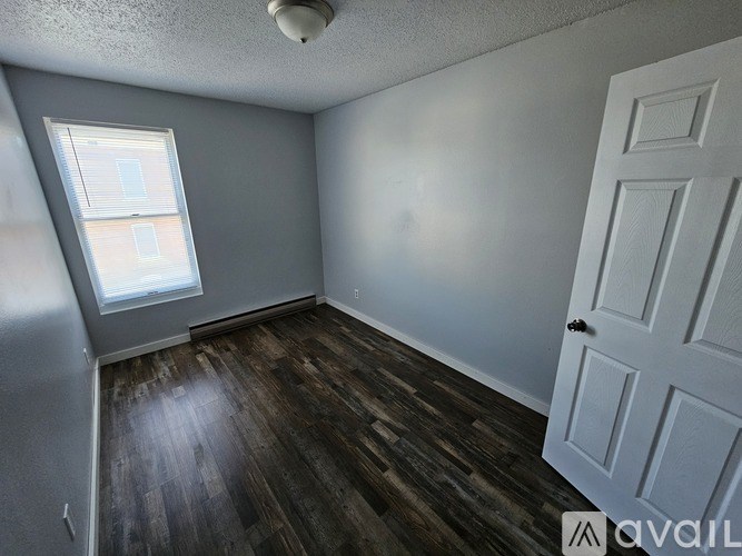 A room with a white door and a window with blinds.