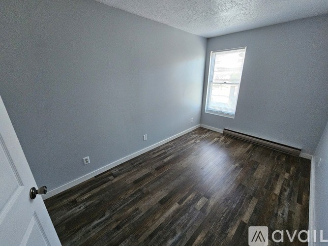 A room with wooden flooring and a window letting in light.