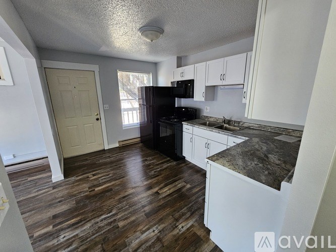 A kitchen with white cabinets and a wooden floor.