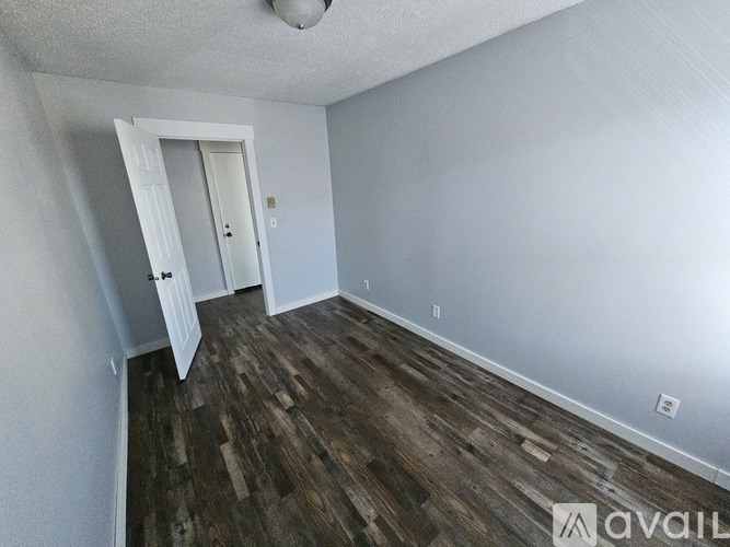 A room with wood flooring and a white door.