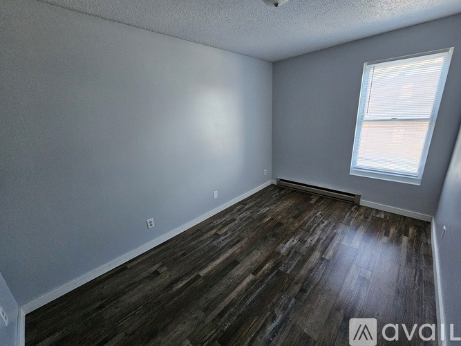 A room with wooden flooring and a window with blinds.