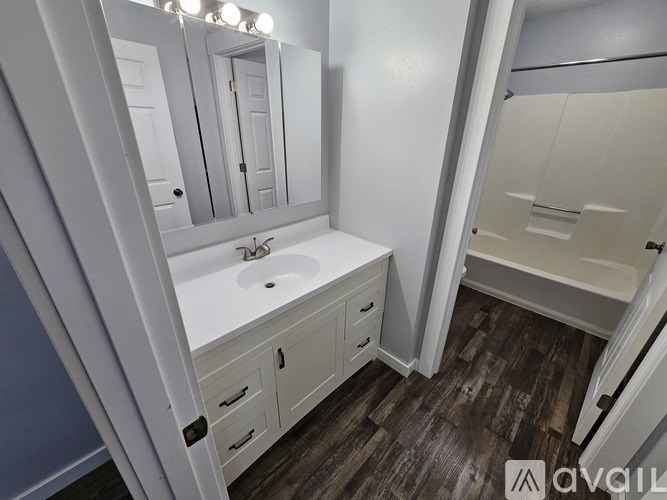 A bathroom with a sink, mirror, and wooden floors.