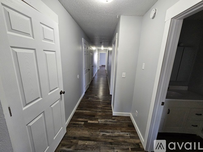 A long hallway with white doors and a wooden floor.