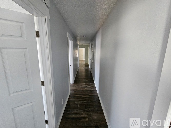 A long hallway with white walls and a wooden floor.