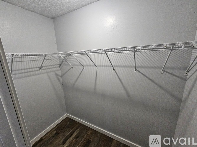 A white closet with a wooden floor and a light on the wall.