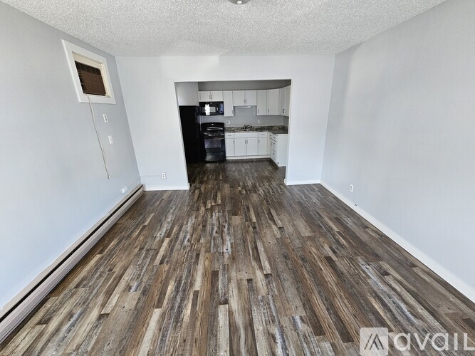 A room with wooden flooring and white walls.