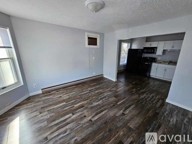 A room with wooden flooring and a window on the left side.