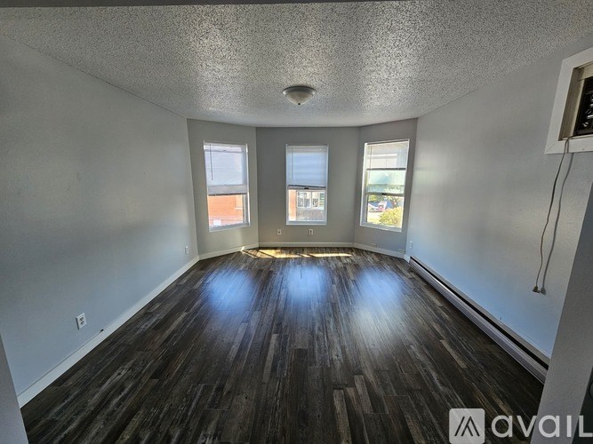 A room with wooden floors and three windows.