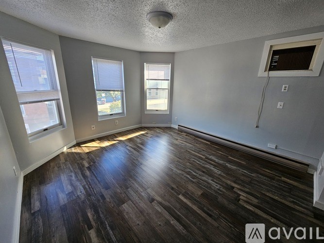 A room with wooden floors and three windows.