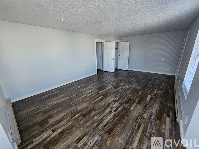 A room with wooden flooring and white walls.