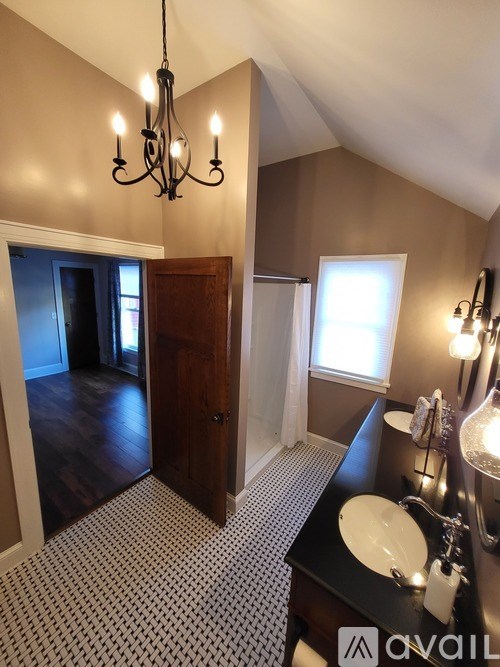 A bathroom with a chandelier, sink, mirror, and a door.