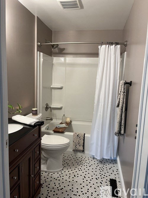 A white toilet sits in a bathroom with a white shower curtain.