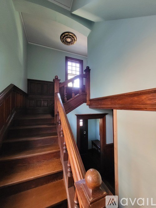 A staircase with a wooden handrail and a window in the background.