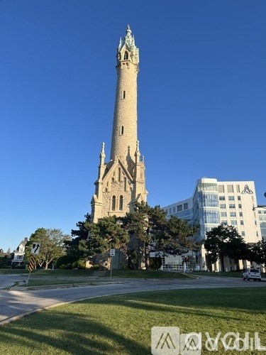 A tall tower with a clock on it stands in front of a modern building.