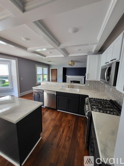 A modern kitchen with dark wood floors and stainless steel appliances.