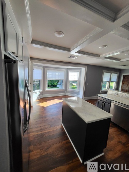 A kitchen with a refrigerator, island, and wooden floors.
