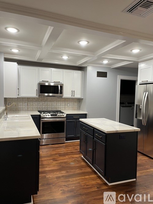 A kitchen with black cabinets and stainless steel appliances.