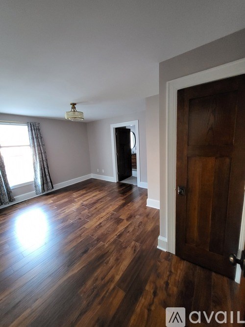 A room with wooden floors and a door on the right.