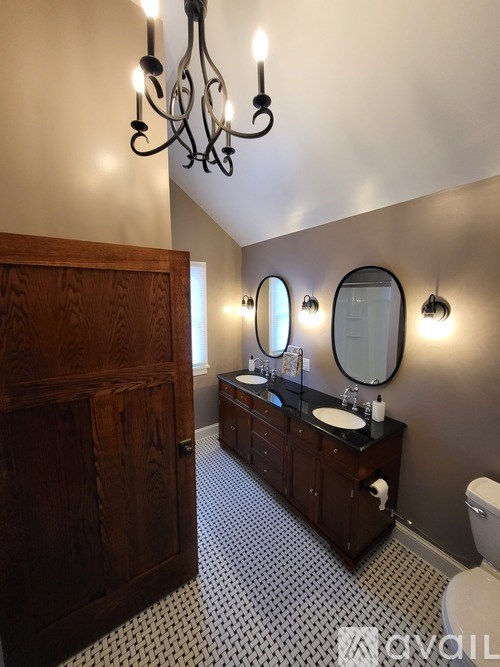 A bathroom with a wooden door and a chandelier.