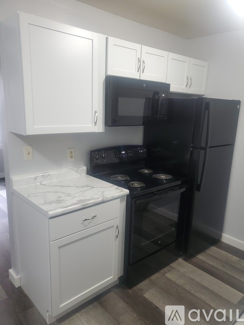 A kitchen with black appliances and white cabinets.