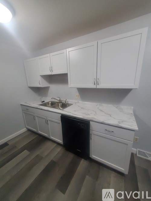 A kitchen with white cabinets and a marble countertop.