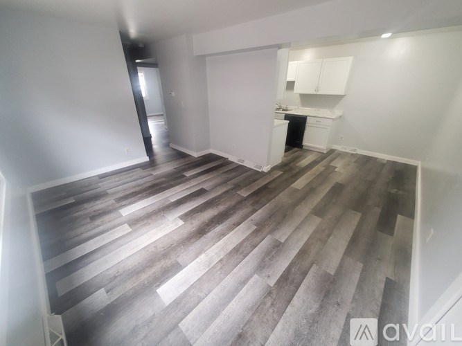 A living room with a kitchen in the background and a staircase leading to the upper floor.
