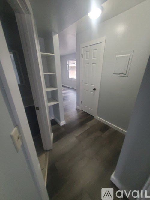 A room with a white door and a white wall with a window.