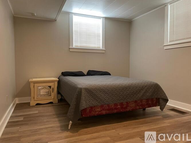 A bedroom with a bed, a nightstand, and a window.