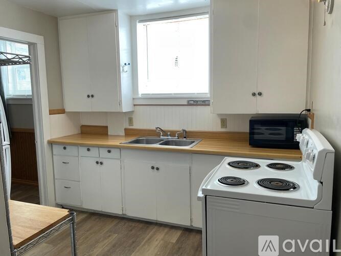 A kitchen with white cabinets and a white stove top oven.