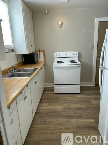 A small kitchen with a white stove and white cabinets.