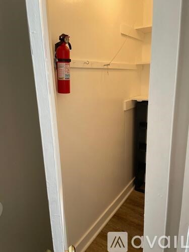 A red fire extinguisher is mounted on a white wall.