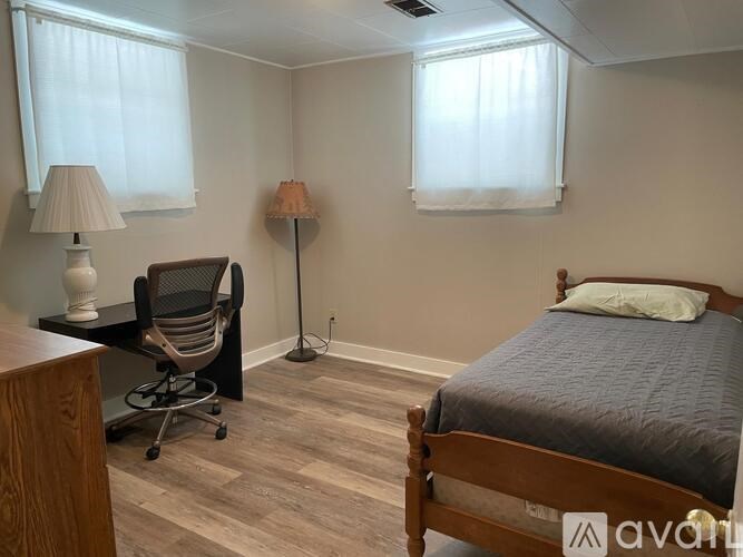 A bedroom with a bed, chair, and two lamps.