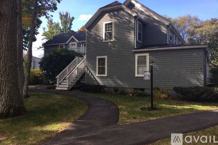 A house with a grey exterior and a tree in front of it.