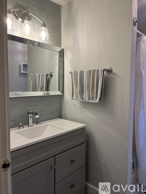 A bathroom with a sink, mirror, and towel rack.