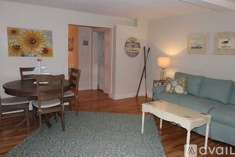 A living room with a couch, a table, and a painting of sunflowers.