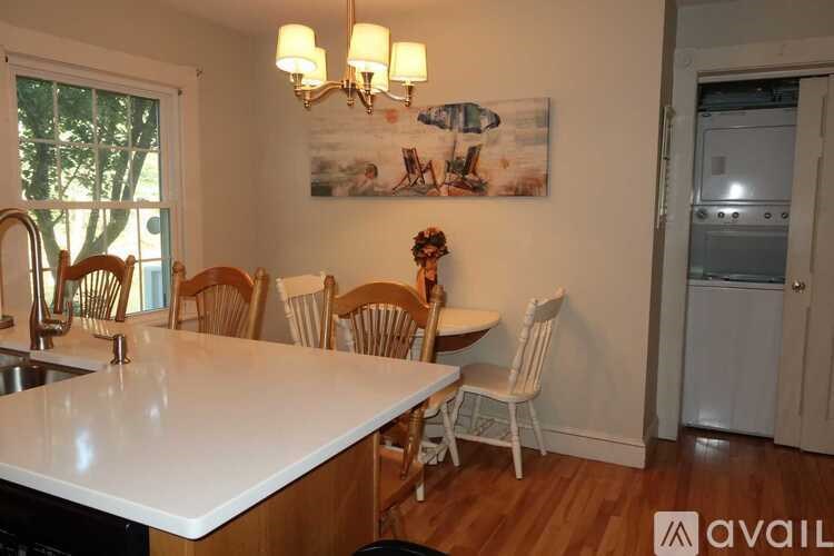 A kitchen with a white countertop and wooden chairs.