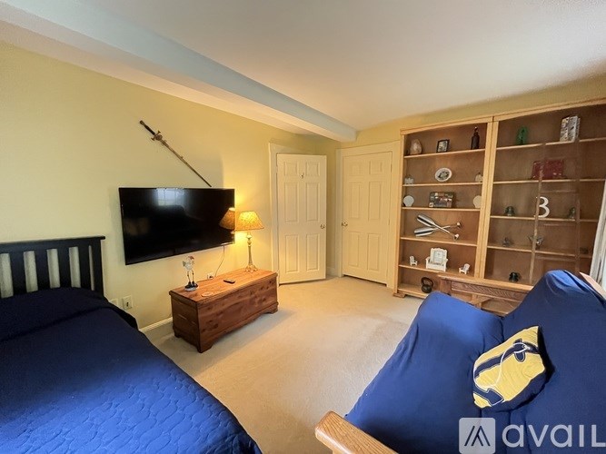 A bedroom with a bed, a chair, and a TV.