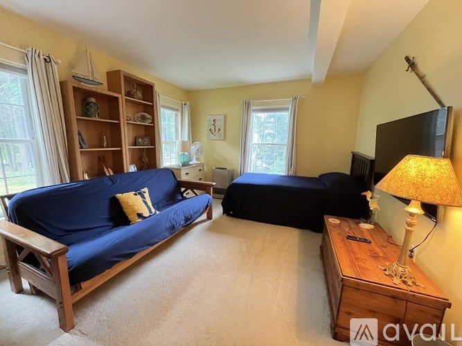 A living room with a blue couch, a wooden shelf, and a lamp.