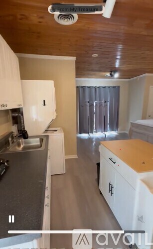 A kitchen with white cabinets and a wooden ceiling.