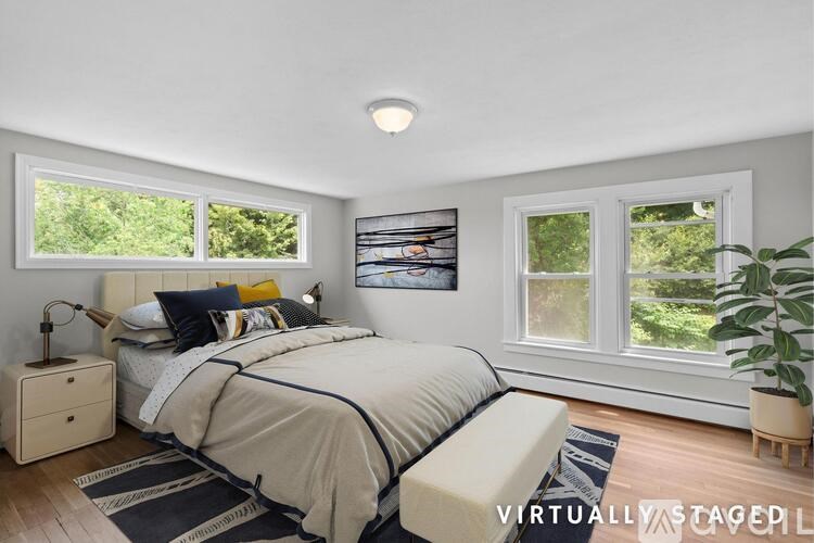 A bedroom with a bed, nightstand, and a potted plant.