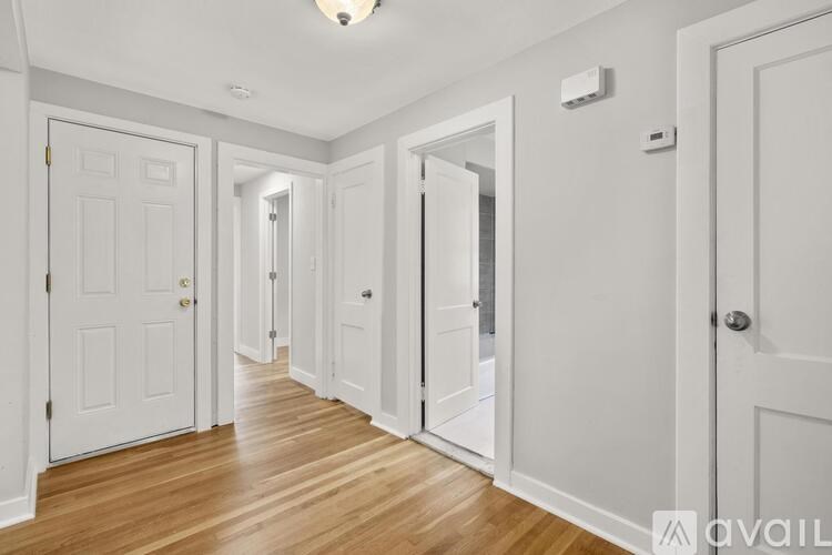 A hallway with white doors and wooden floors.