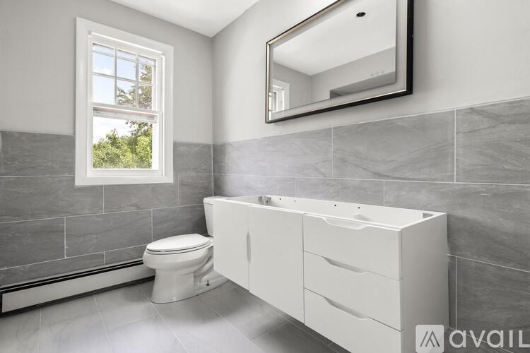 A bathroom with a toilet, sink, and a window.