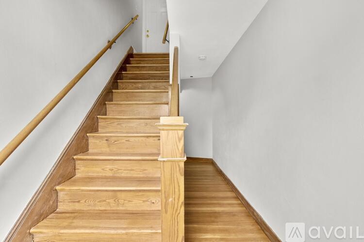 A wooden staircase with a white wall on the side.