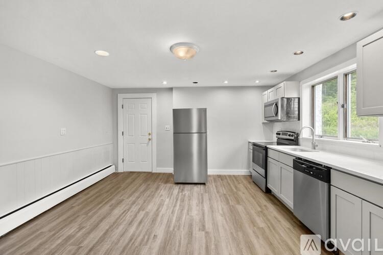 A kitchen with a wooden floor and stainless steel appliances.