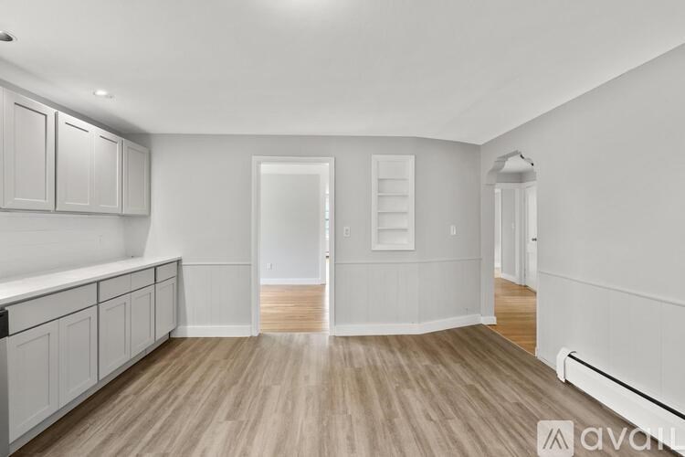 A spacious kitchen with white cabinets and a wooden floor.