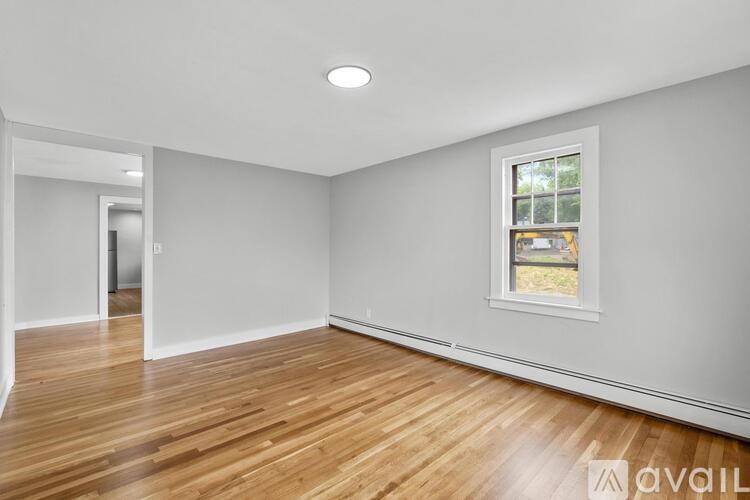A room with wooden floors and a window showing a view of a yard.