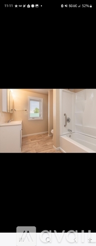 A bathroom with a white bathtub and a window.