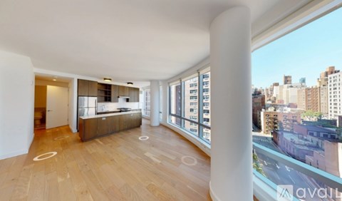 A large open living space with wooden floors and a view of the city.