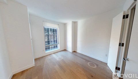 A room with a window and wooden flooring.
