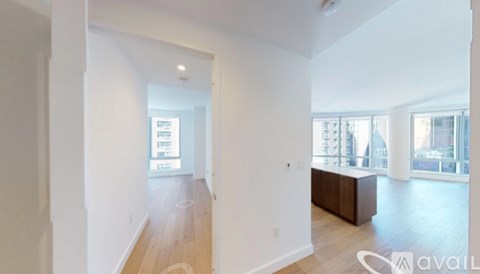 A spacious room with wooden floors and white walls, with a large window on the right side.